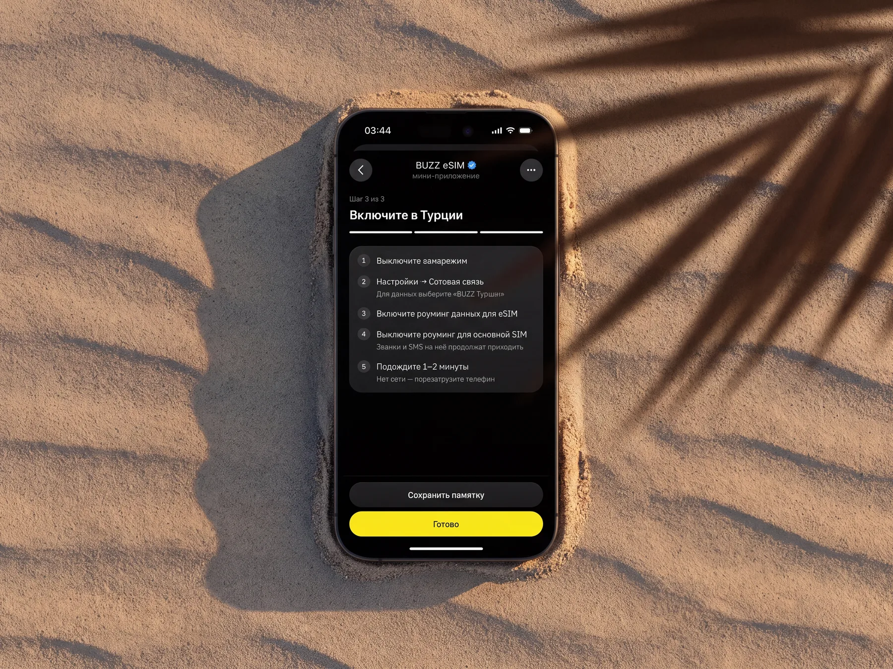 Switch-on steps on a phone in the sand under the shadow of a palm leaf
